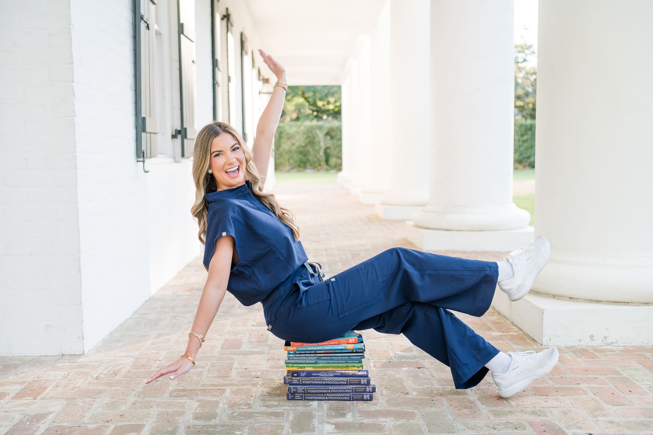 LSUE senior sitting on books celebrating graduating college