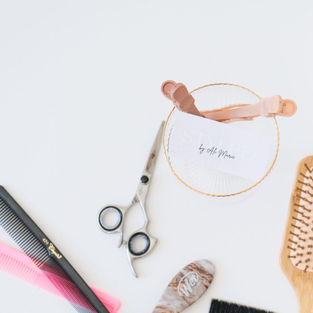 Hair styling tools: brush, comb, scissors, clips displayed in branding photoshoot