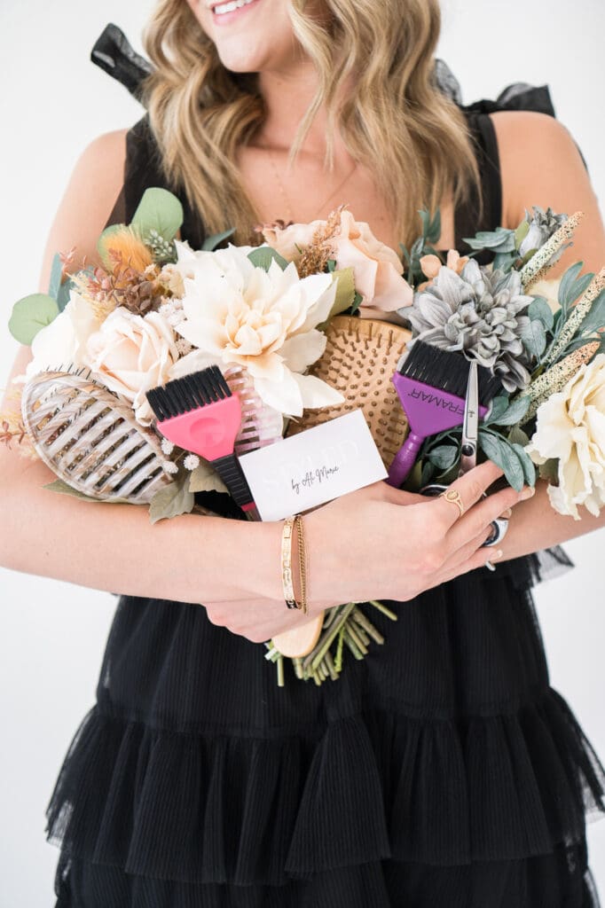 Hairstylist holding bouquet of flowers with hair styling tools