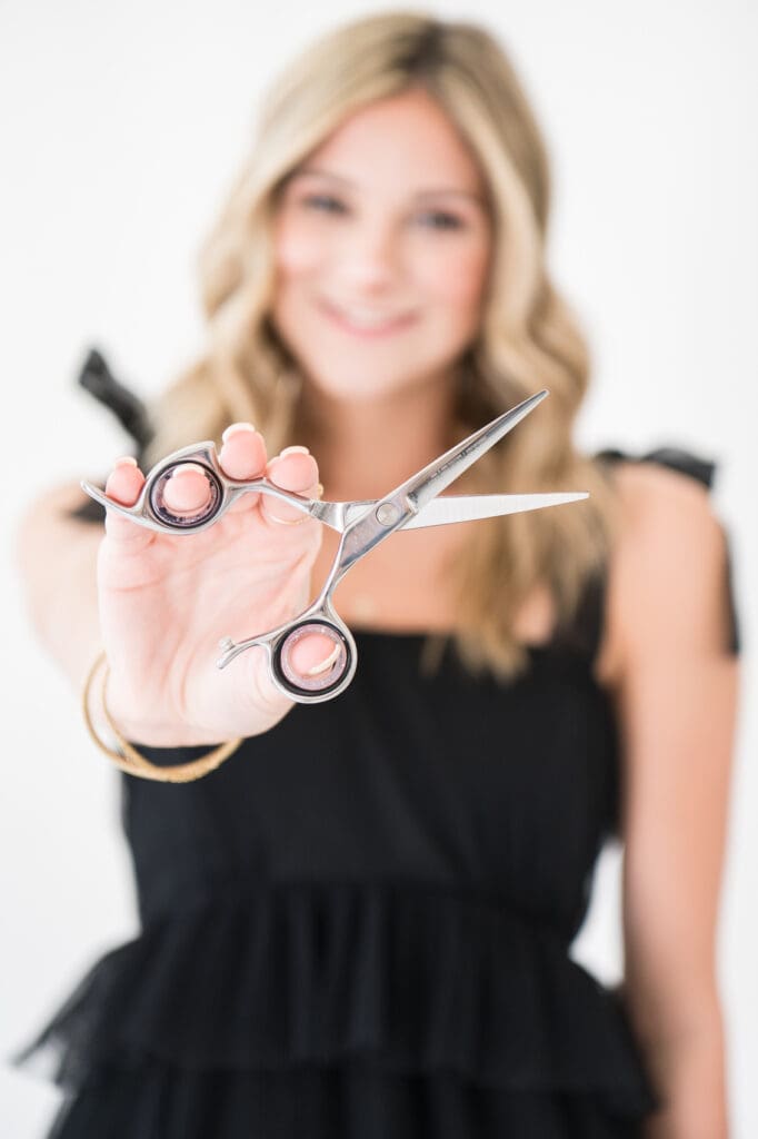 Hairstylist holding scissors out in front of her
