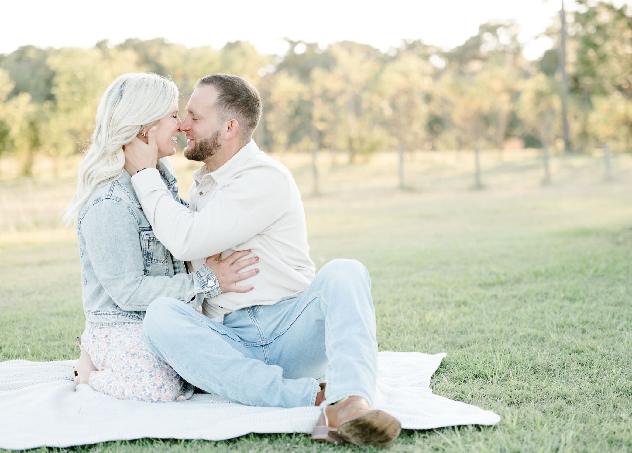 South Louisiana portrait session of couple sitting on blanket about to kiss at a flower farm.